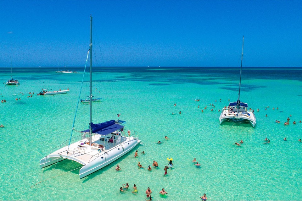 Catamarans and swimmers in turquoise water near Saona Island